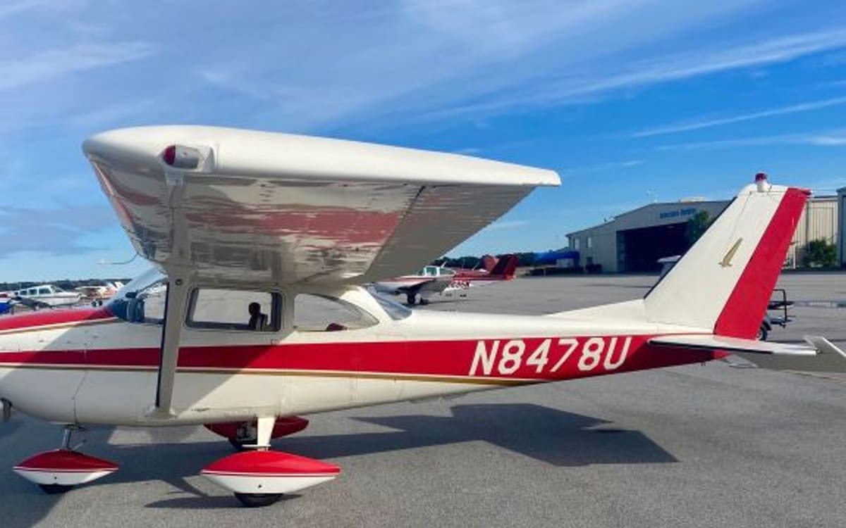 A red-and-white Cessna 172 Skyhawk registered N8478U on the ramp, seen from the front quarter beneath its wing.